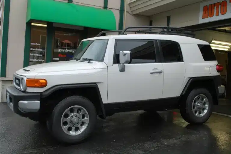 Toyota Cruiser with tinted windows parked outside an auto tinting shop.