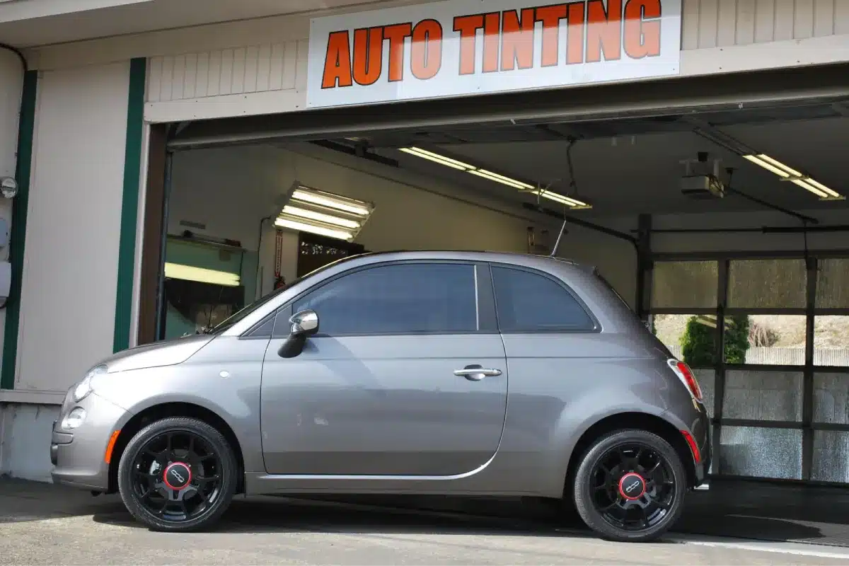 a car with tinted windows in front of an auto tinting shop.