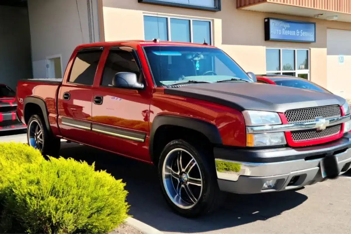 Red and black Chevrolet Silverado truck parked outside a building with modern design.