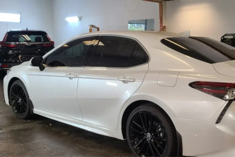 White sedan with dark window tint in a detail shop.