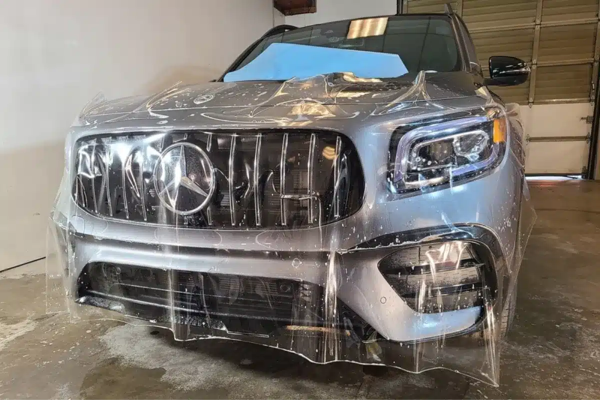 Clear paint protection film being applied to front of a Mercedes SUV.